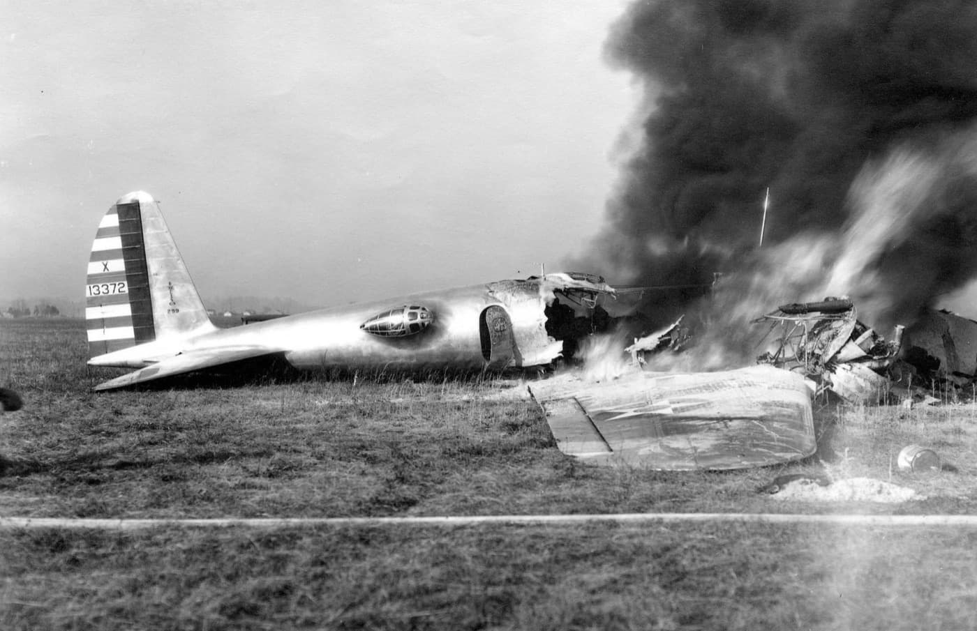 The Boeing Model 299 burning in a field at Wright Field after the crash, its tail intact and the forward fuselage in smoke
